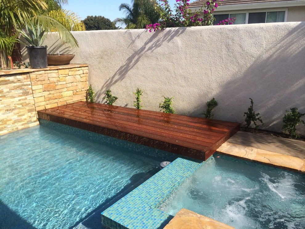 Diseño de piscina con fuente alargada actual grande rectangular en patio trasero con losas de hormigón