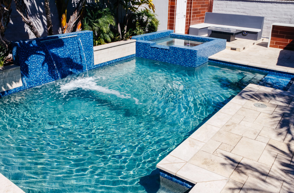 Photo of a medium sized modern back custom shaped swimming pool in Orange County with a water feature and concrete paving.
