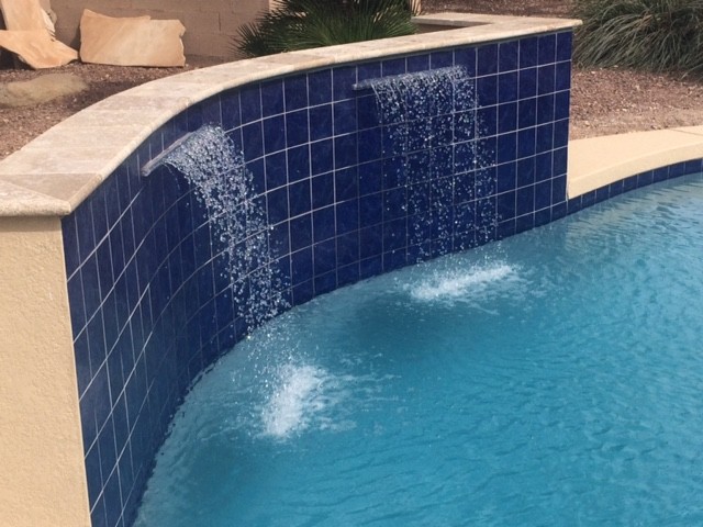 Immagine di una piscina mediterranea personalizzata di medie dimensioni e dietro casa con fontane e piastrelle