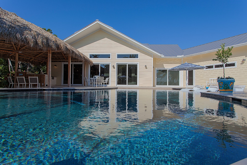 Immagine di una piscina tropicale personalizzata di medie dimensioni e dietro casa con una dépendance a bordo piscina e pavimentazioni in pietra naturale