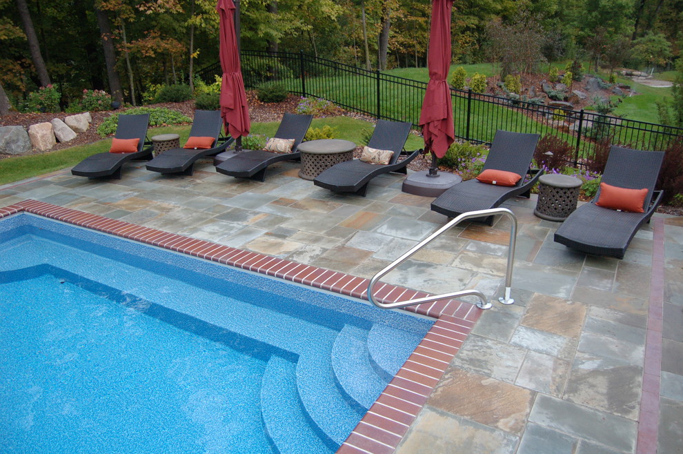 Idées déco pour une grande piscine naturelle et arrière classique rectangle avec des pavés en pierre naturelle.