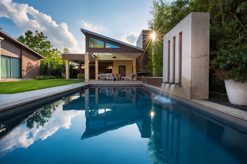 На фото: прямоугольный бассейн среднего размера на заднем дворе в стиле модернизм с домиком у бассейна и покрытием из бетонных плит