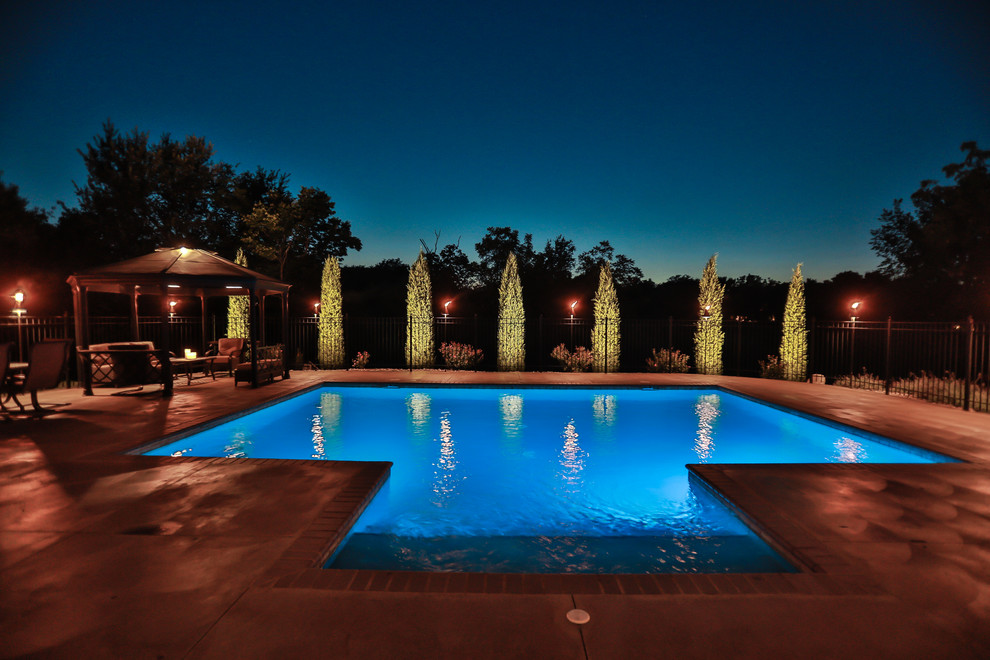 Modelo de piscina natural marinera grande rectangular en patio trasero con losas de hormigón