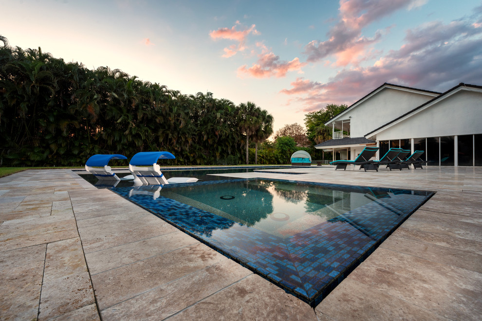 Diseño de piscinas y jacuzzis alargados modernos grandes en forma de L en patio trasero con adoquines de piedra natural