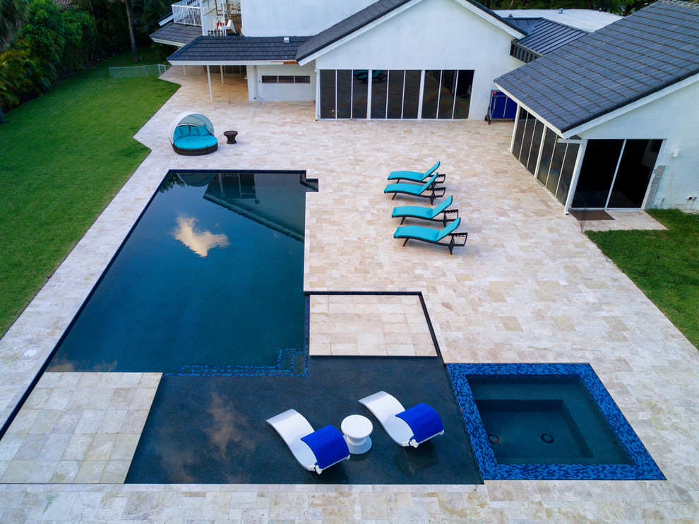 Ispirazione per una grande piscina monocorsia minimalista a "L" dietro casa con una vasca idromassaggio e pavimentazioni in pietra naturale