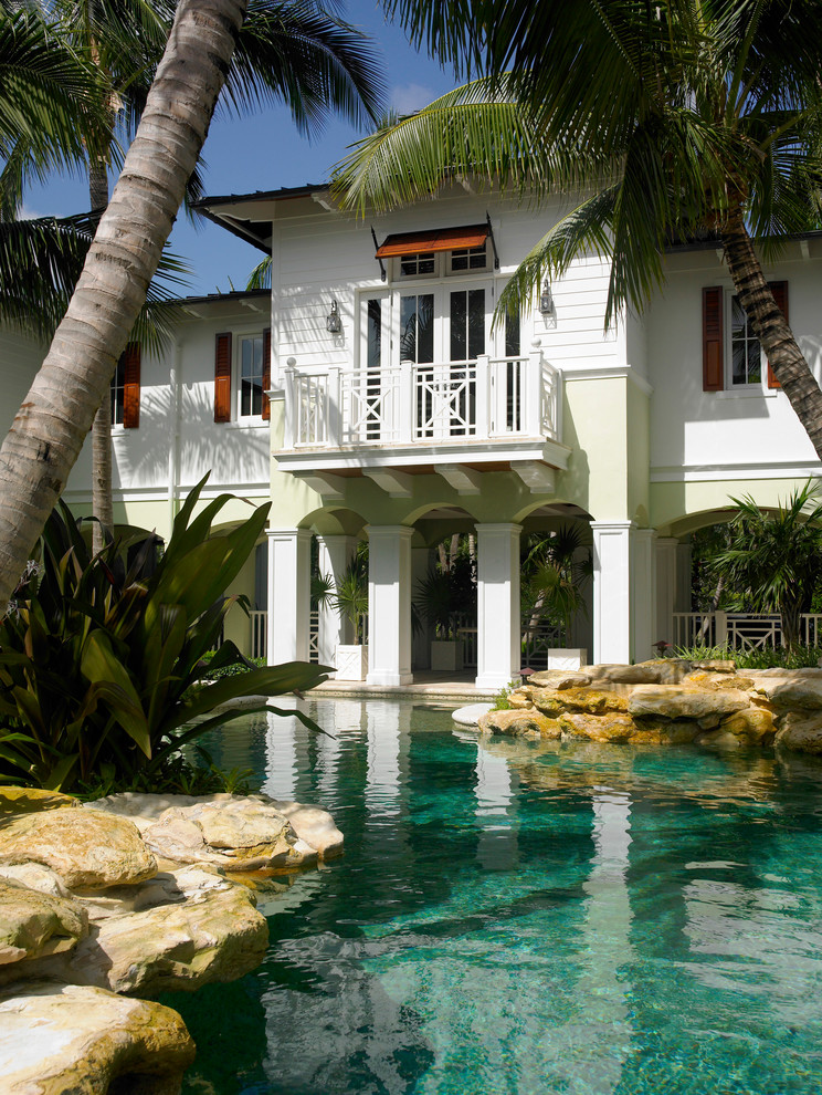 Exotisk inredning av en stor anpassad pool på baksidan av huset, med naturstensplattor