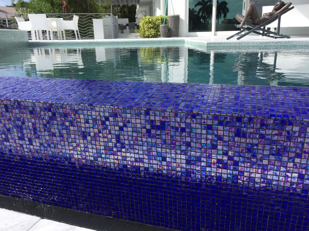 Idee per una piscina a sfioro infinito minimal personalizzata di medie dimensioni e dietro casa con fontane e piastrelle