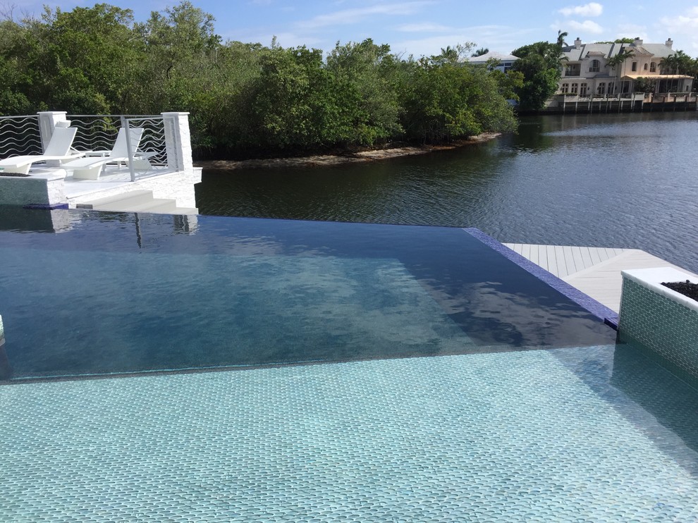 Immagine di una piscina a sfioro infinito contemporanea personalizzata dietro casa e di medie dimensioni con fontane e piastrelle