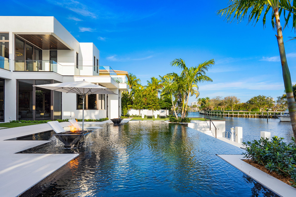 Großer, Gefliester Moderner Infinity-Pool hinter dem Haus in rechteckiger Form mit Wasserspiel in Miami