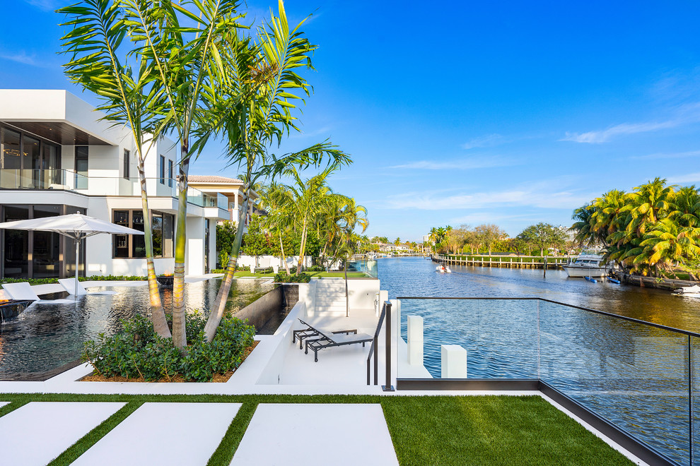 Modelo de piscinas y jacuzzis infinitos minimalistas grandes rectangulares en patio trasero con suelo de baldosas