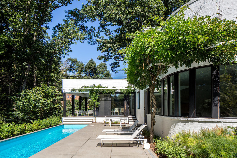 Esempio di una grande piscina monocorsia minimal rettangolare dietro casa con lastre di cemento