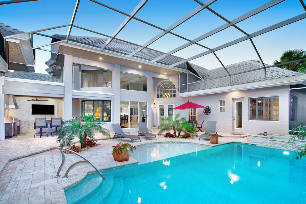 Hot tub - large tropical backyard concrete paver and rectangular hot tub idea in Miami