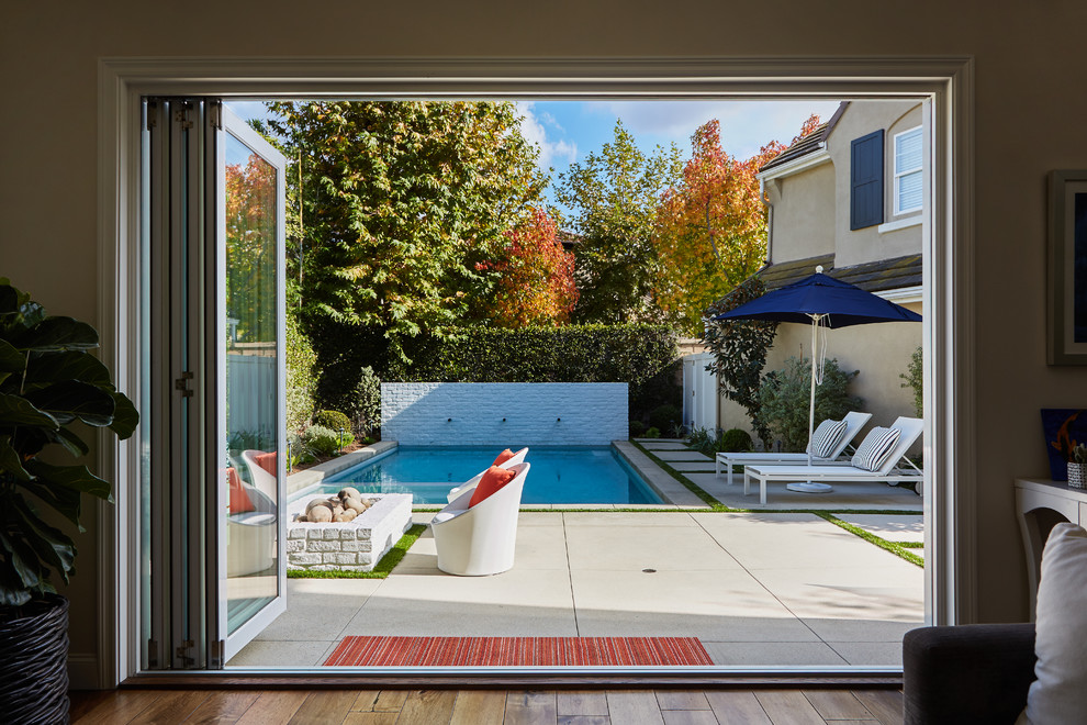 Mittelgroßer Moderner Pool hinter dem Haus in rechteckiger Form mit Wasserspiel und Betonboden in Orange County