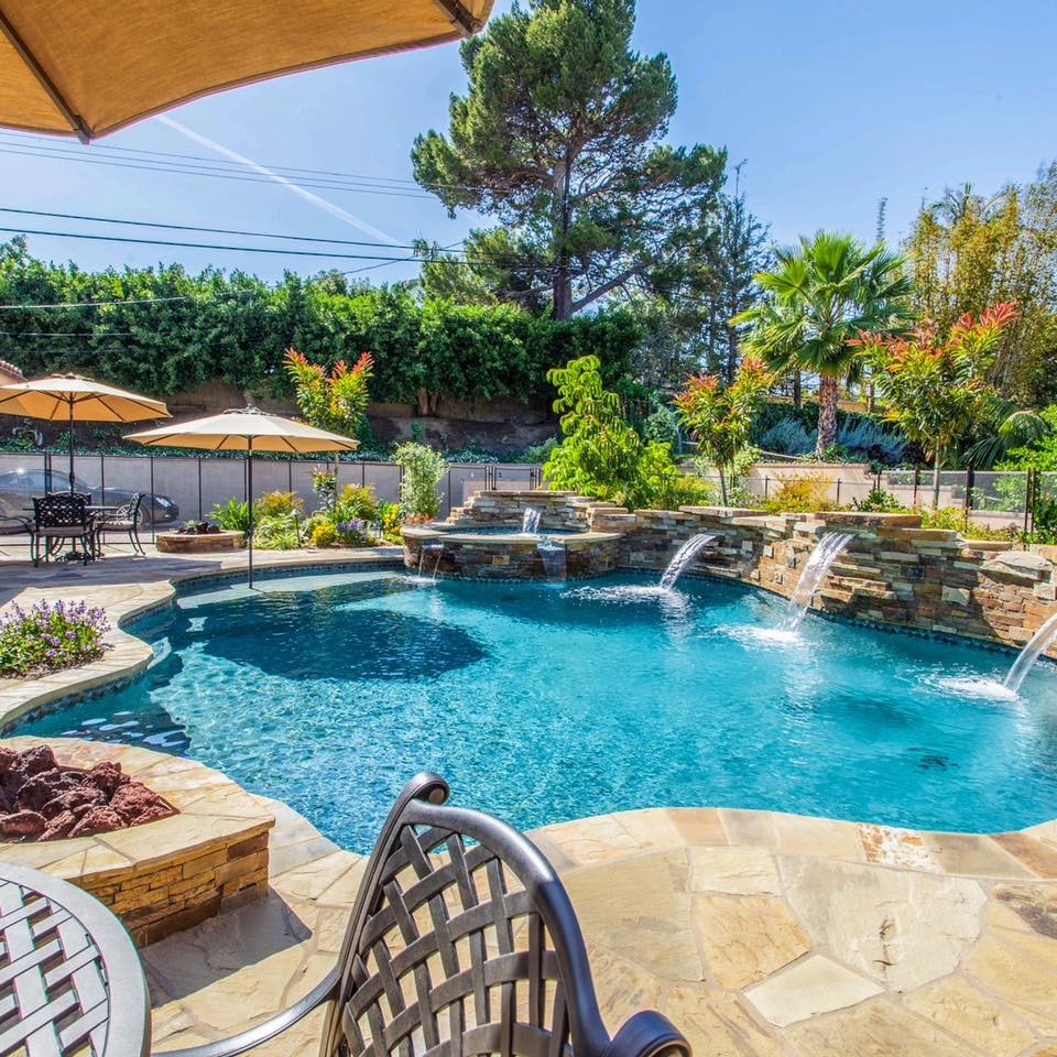 Imagen de piscina con fuente natural clásica renovada de tamaño medio a medida en patio trasero con adoquines de piedra natural