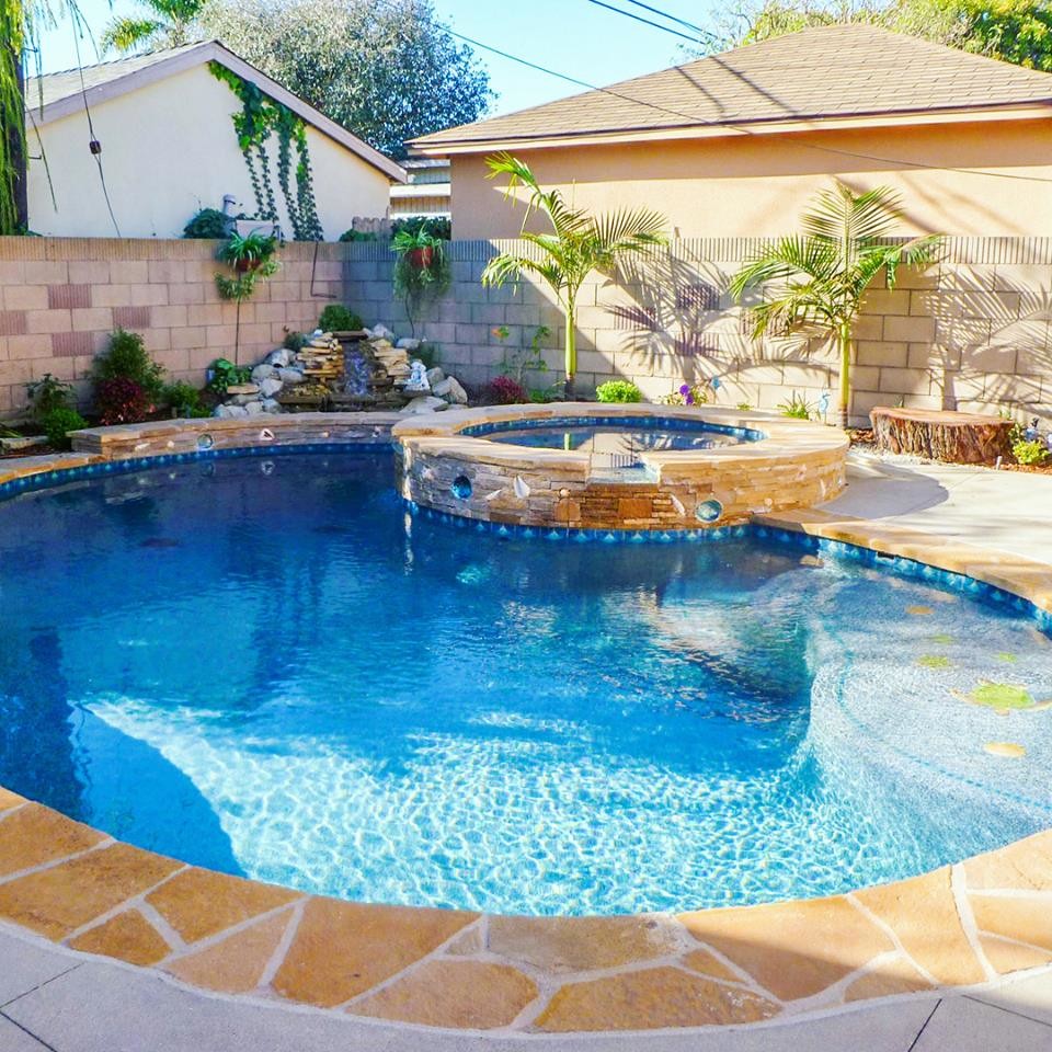 Immagine di una piscina naturale stile marino a "C" dietro casa e di medie dimensioni con una vasca idromassaggio e pavimentazioni in pietra naturale