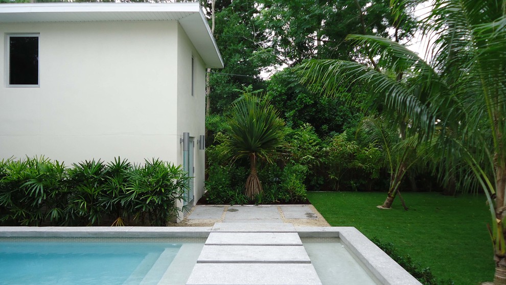 Inredning av en exotisk mellanstor pool på baksidan av huset, med en fontän och betongplatta