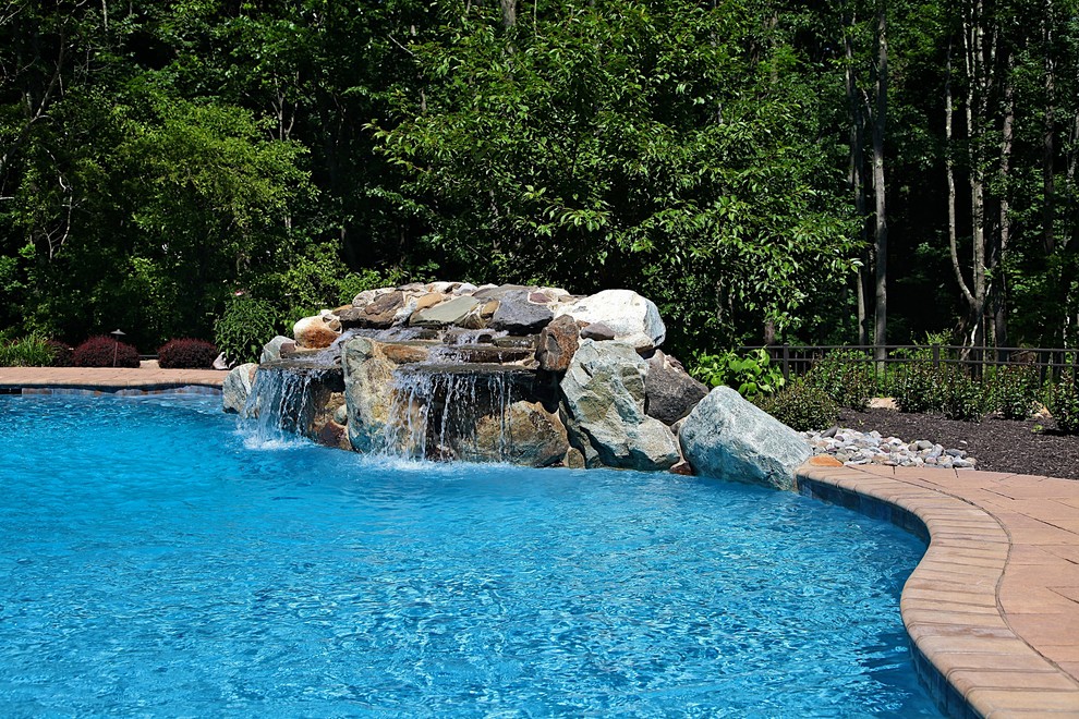 На фото: бассейн среднего размера, произвольной формы на заднем дворе в стиле рустика с фонтаном и мощением клинкерной брусчаткой