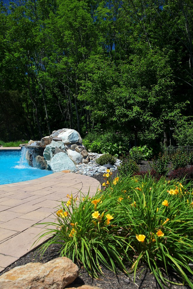 Ejemplo de piscina con fuente rural de tamaño medio a medida en patio trasero con adoquines de ladrillo