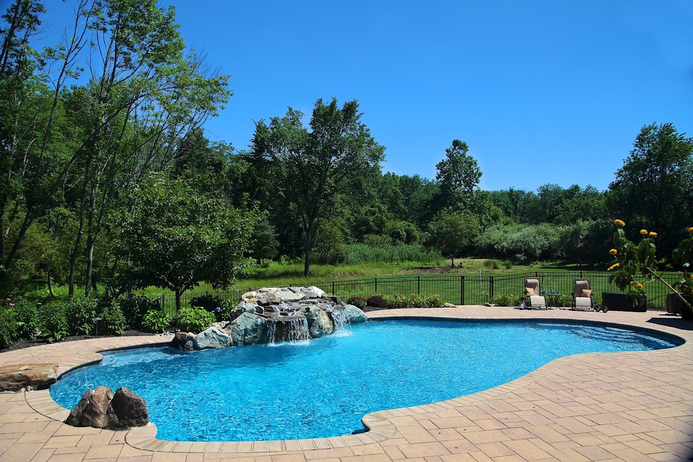 Ejemplo de piscina con fuente rústica de tamaño medio a medida en patio trasero con adoquines de ladrillo