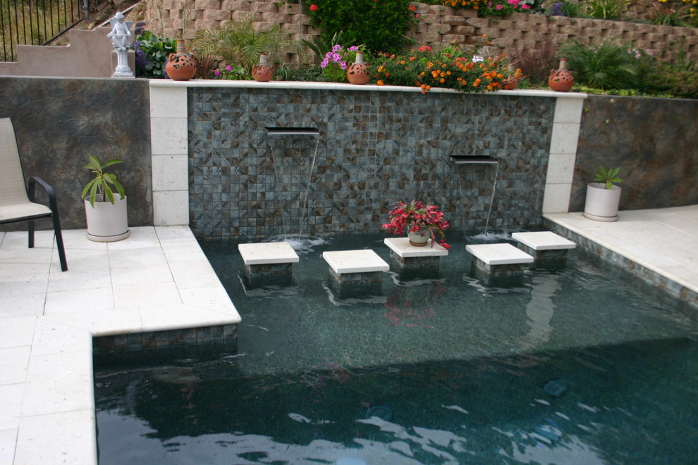Foto de piscina con fuente alargada minimalista pequeña rectangular en patio trasero con adoquines de hormigón
