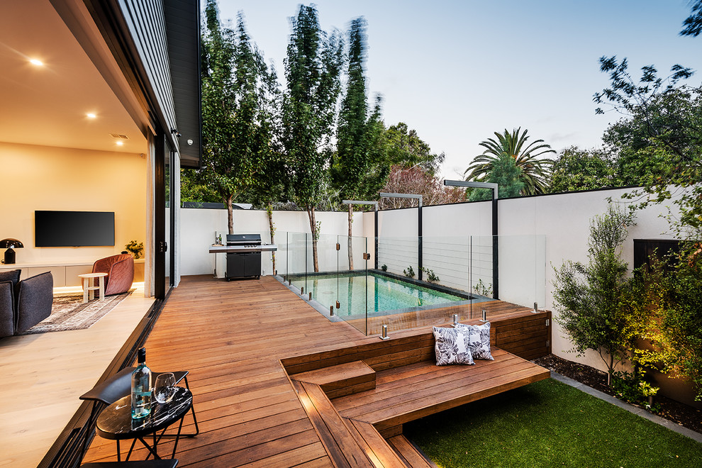 Cette image montre une petite piscine arrière design rectangle avec une terrasse en bois.