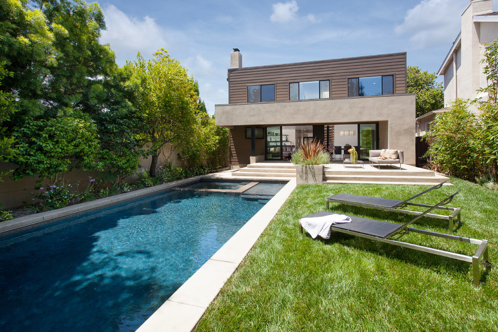 Imagen de piscina alargada actual grande rectangular en patio trasero con losas de hormigón