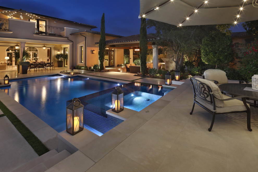 Foto de piscinas y jacuzzis infinitos contemporáneos grandes rectangulares en patio trasero con adoquines de piedra natural