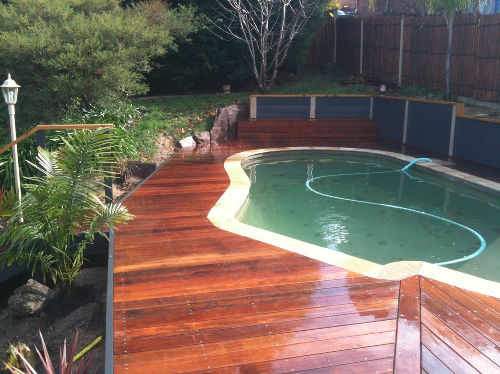 Exemple d'une piscine naturelle et arrière moderne en forme de haricot de taille moyenne avec une terrasse en bois.