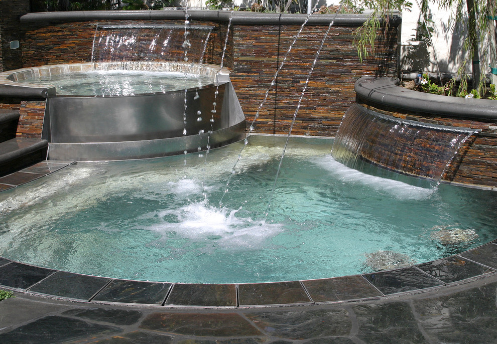 Diseño de piscina con fuente elevada rural a medida en patio trasero con adoquines de piedra natural