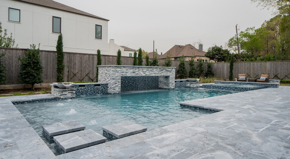 Réalisation d'une grande piscine arrière design rectangle avec des pavés en pierre naturelle.