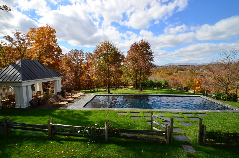 Immagine di una grande piscina monocorsia classica rettangolare dietro casa con pavimentazioni in pietra naturale e una dépendance a bordo piscina