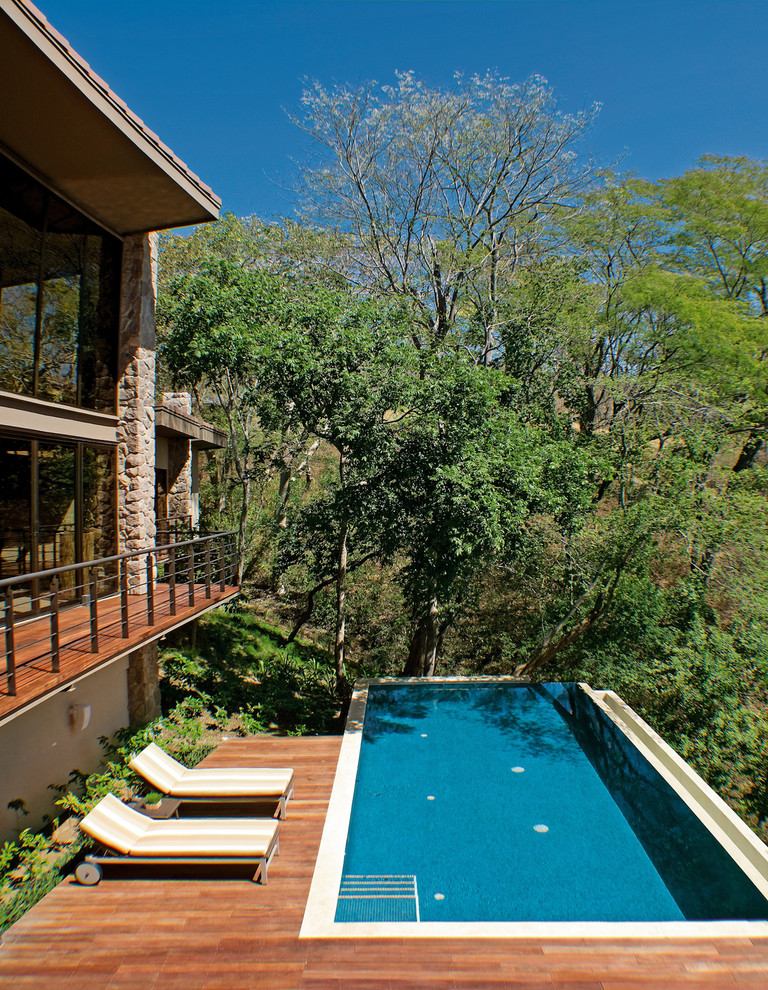 Aménagement d'une piscine à débordement et arrière contemporaine de taille moyenne et rectangle avec une terrasse en bois.