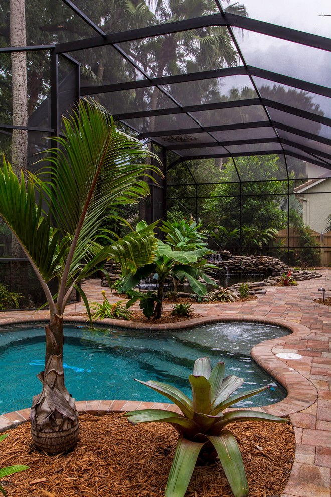 Modelo de piscina con fuente natural tropical grande a medida en patio trasero con adoquines de ladrillo