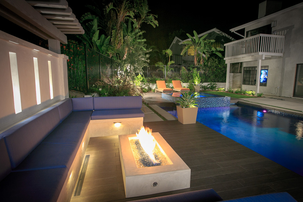 Imagen de piscina con fuente natural actual de tamaño medio rectangular en patio trasero con suelo de baldosas