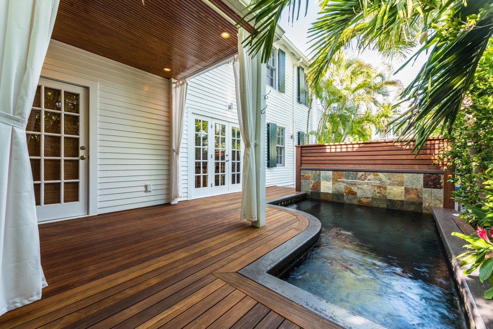 Foto de piscina con fuente exótica pequeña en forma de L en patio trasero con entablado