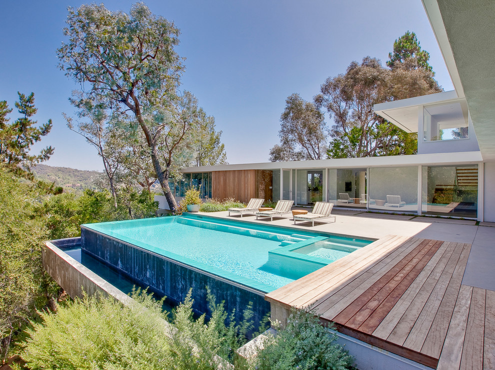 Inspiration pour une piscine à débordement minimaliste avec une terrasse en bois.