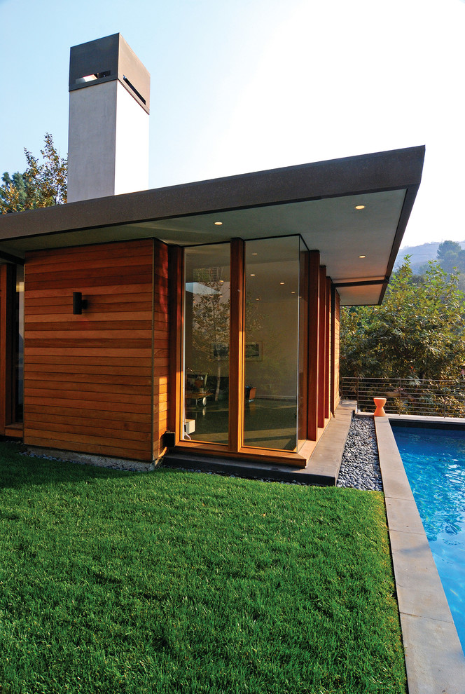 Foto de piscina alargada minimalista grande rectangular en patio trasero con losas de hormigón