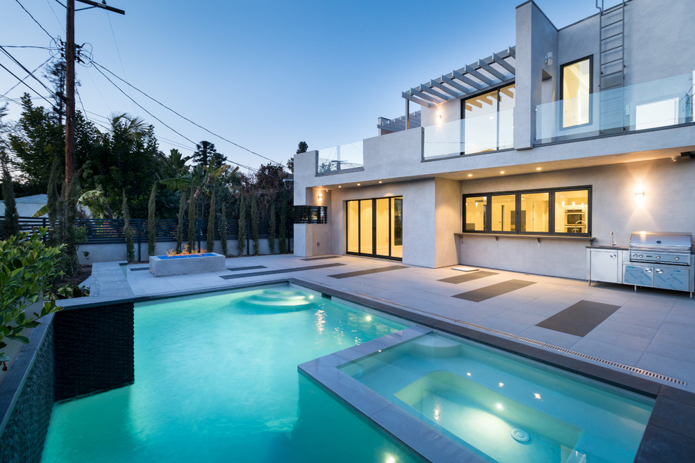 Immagine di una piscina design rettangolare dietro casa con pavimentazioni in cemento