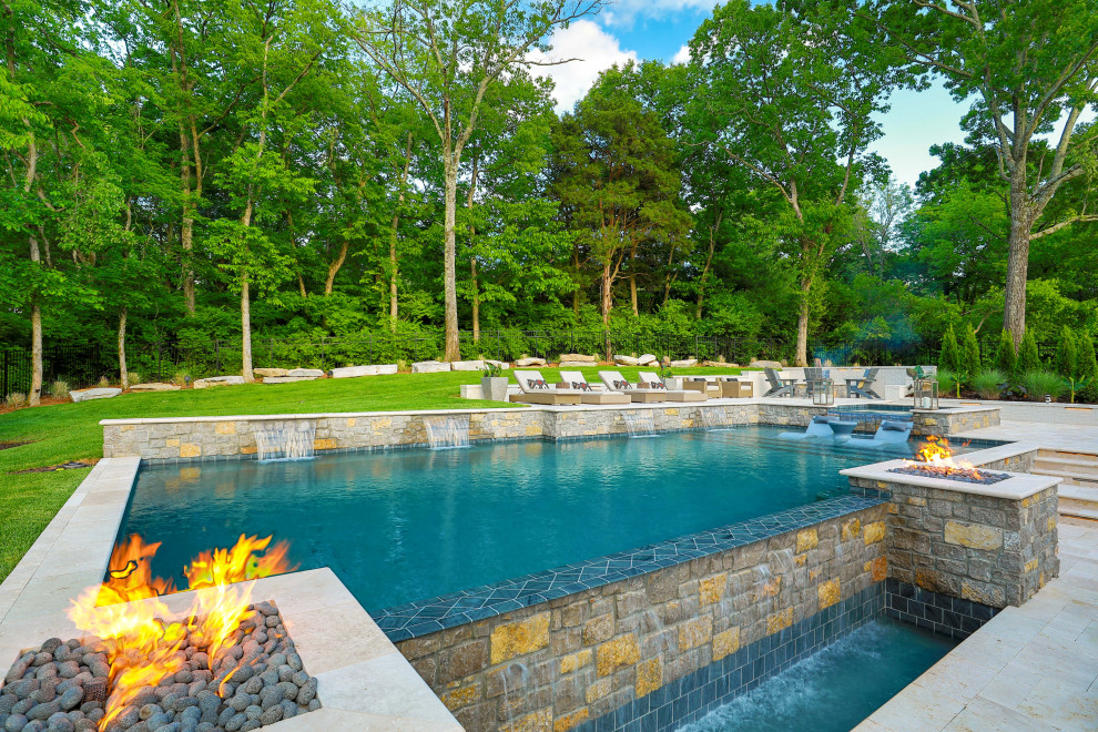 Cette photo montre une grande piscine à débordement et arrière chic rectangle avec un bain bouillonnant et des pavés en pierre naturelle.