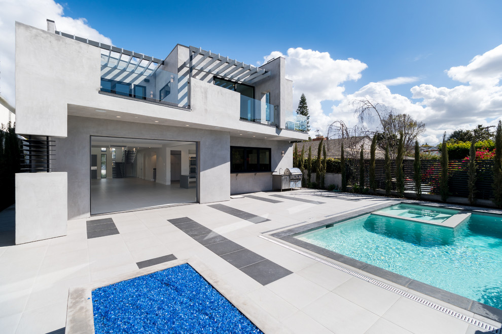 Foto di una grande piscina design rettangolare dietro casa con una vasca idromassaggio e pavimentazioni in cemento