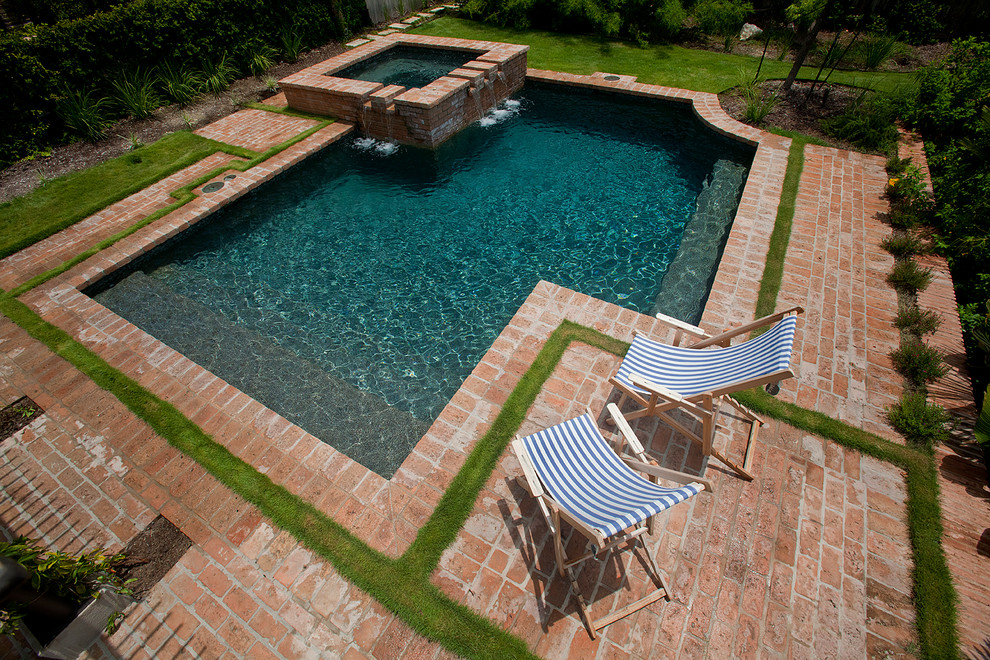 Esempio di una piccola piscina monocorsia tradizionale personalizzata dietro casa con pavimentazioni in mattoni e una vasca idromassaggio