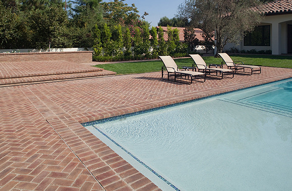 Imagen de piscina alargada de estilo americano grande rectangular en patio trasero con adoquines de ladrillo