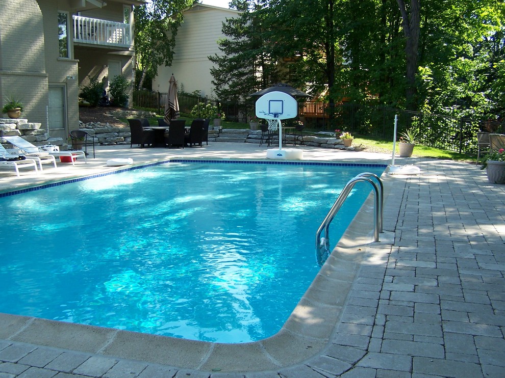 Foto de piscina tradicional de tamaño medio en patio trasero con adoquines de ladrillo