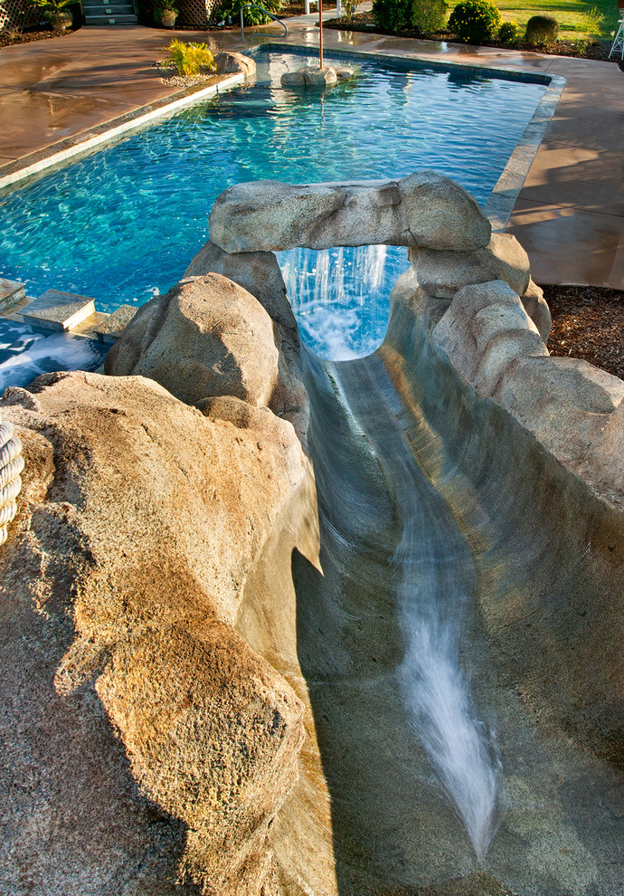 Mittelgroßer Pool hinter dem Haus in rechteckiger Form mit Wasserrutsche und Betonplatten in San Diego