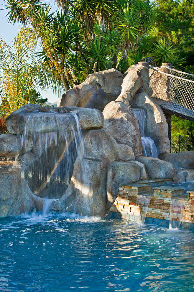 Esempio di una piscina tropicale rettangolare con un acquascivolo