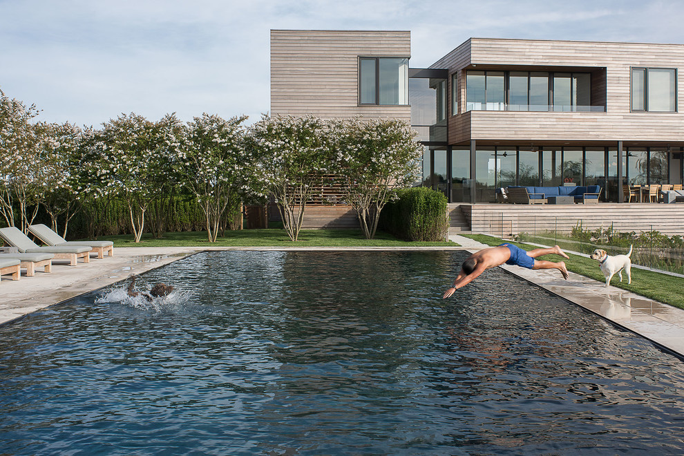 На фото: огромный прямоугольный бассейн на заднем дворе в морском стиле с покрытием из бетонных плит