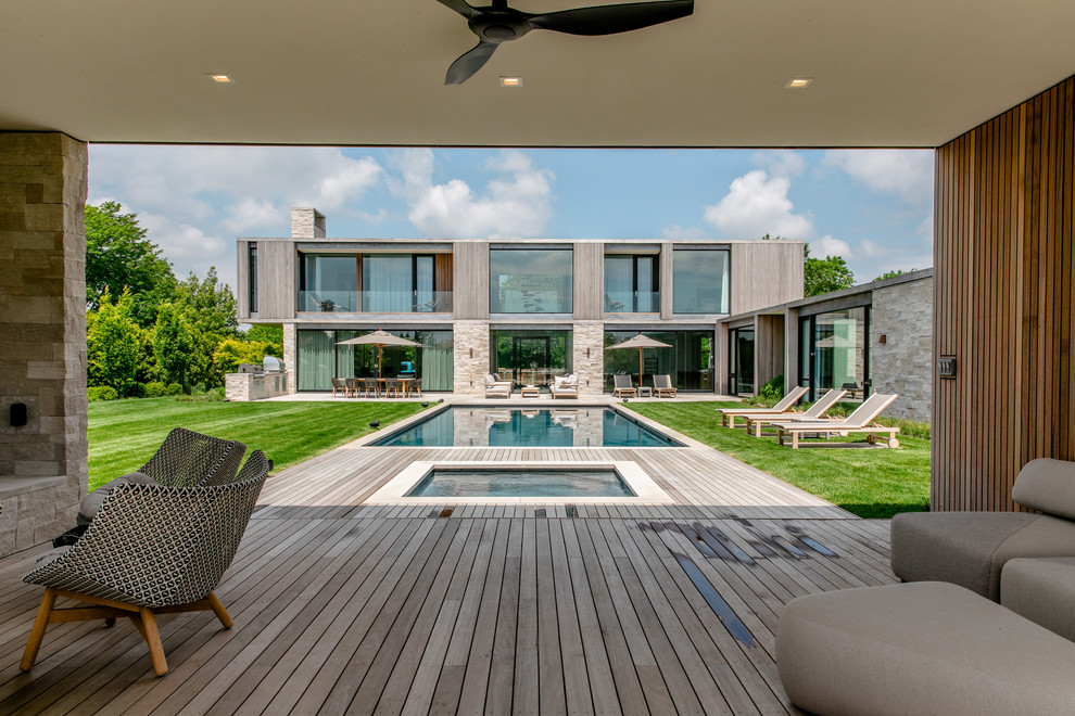 Idée de décoration pour un grand Abris de piscine et pool houses arrière design rectangle avec une terrasse en bois.