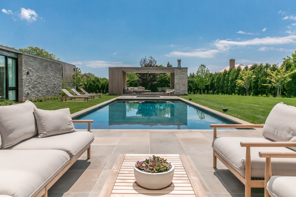 Inspiration for a large contemporary back rectangular swimming pool in New York with natural stone paving.