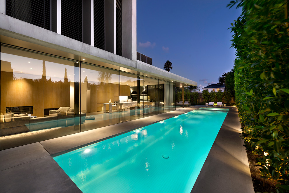 Esempio di una grande piscina monocorsia minimalista rettangolare dietro casa con una vasca idromassaggio e lastre di cemento