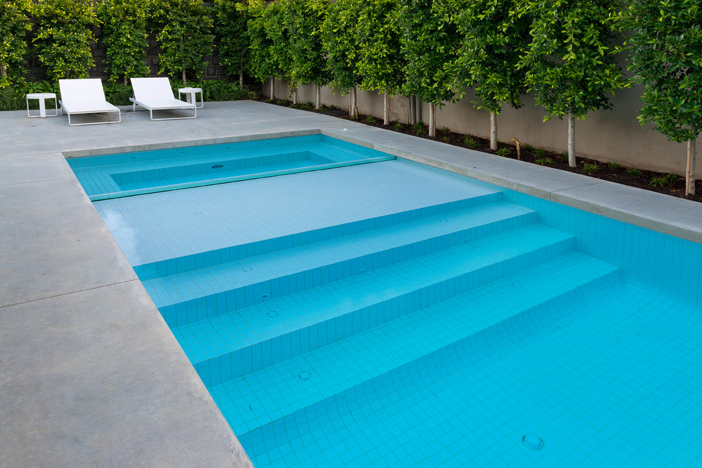 Esempio di una grande piscina monocorsia moderna rettangolare dietro casa con lastre di cemento e una vasca idromassaggio